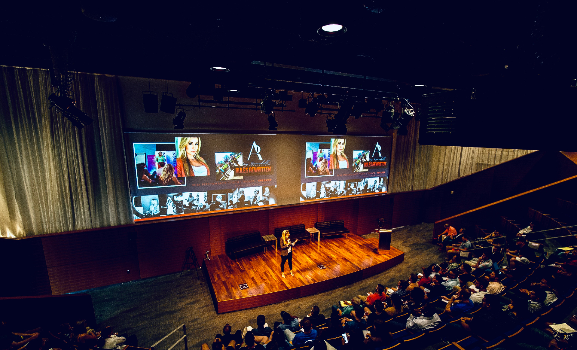 Amy speaking on stage in auditorium
